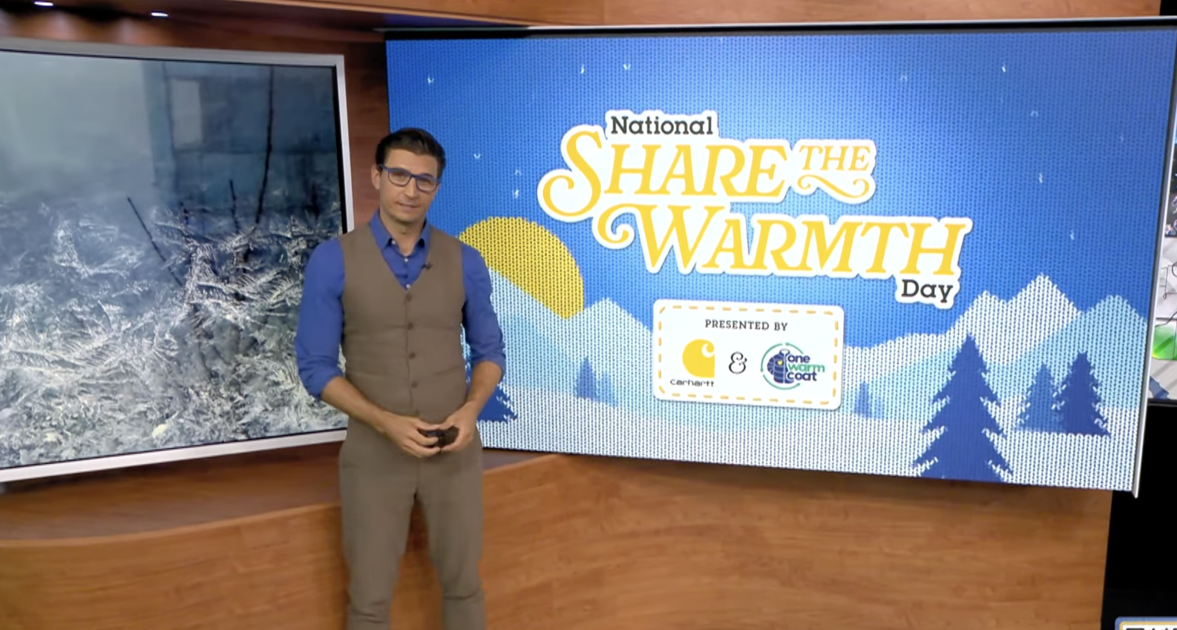 Presenter standing beside a “Share the Warmth Day” display.